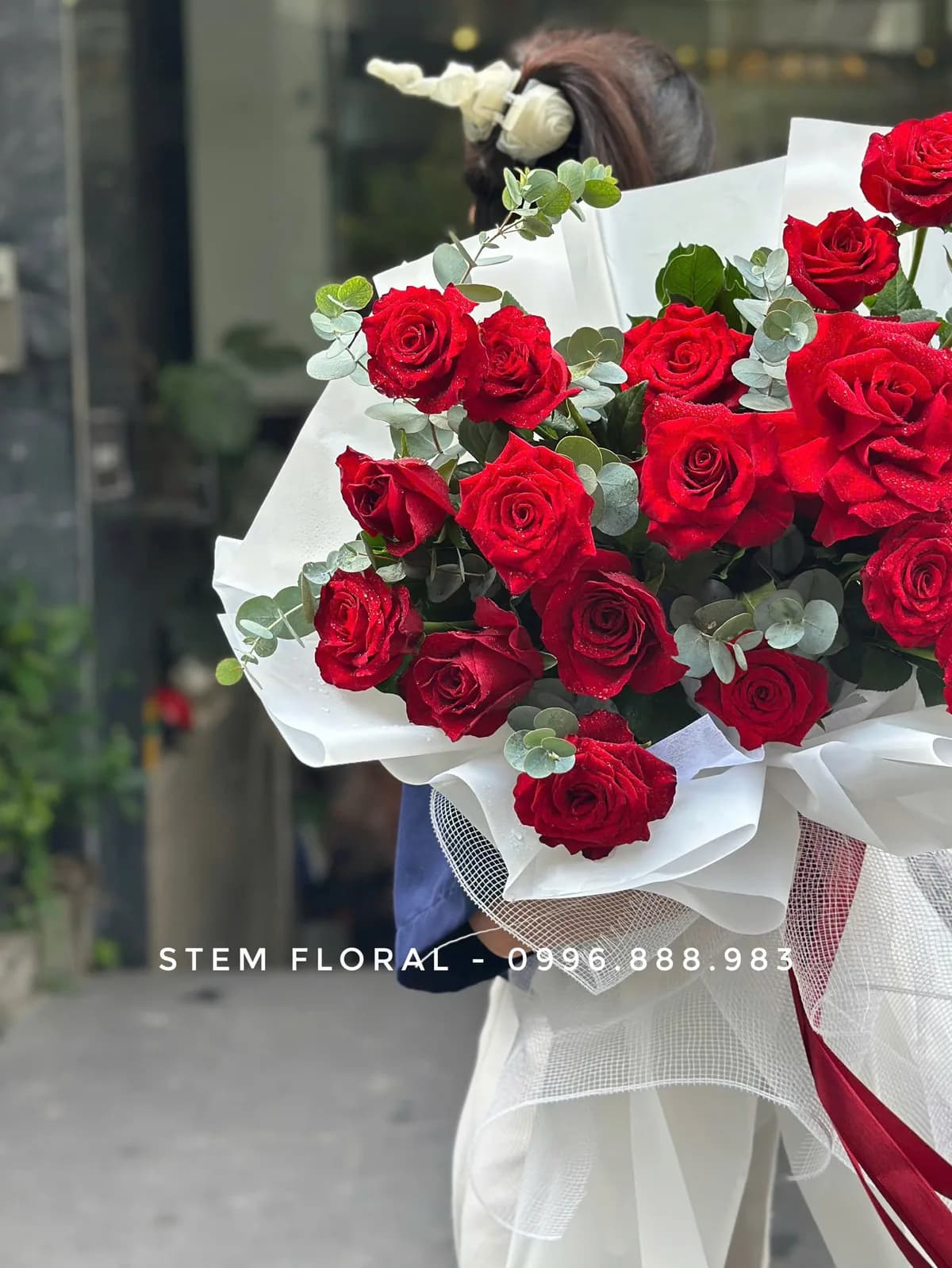 Hoa hồng đỏ nổi bật giữa lá xanh và giấy gói trắng — Stem Floral