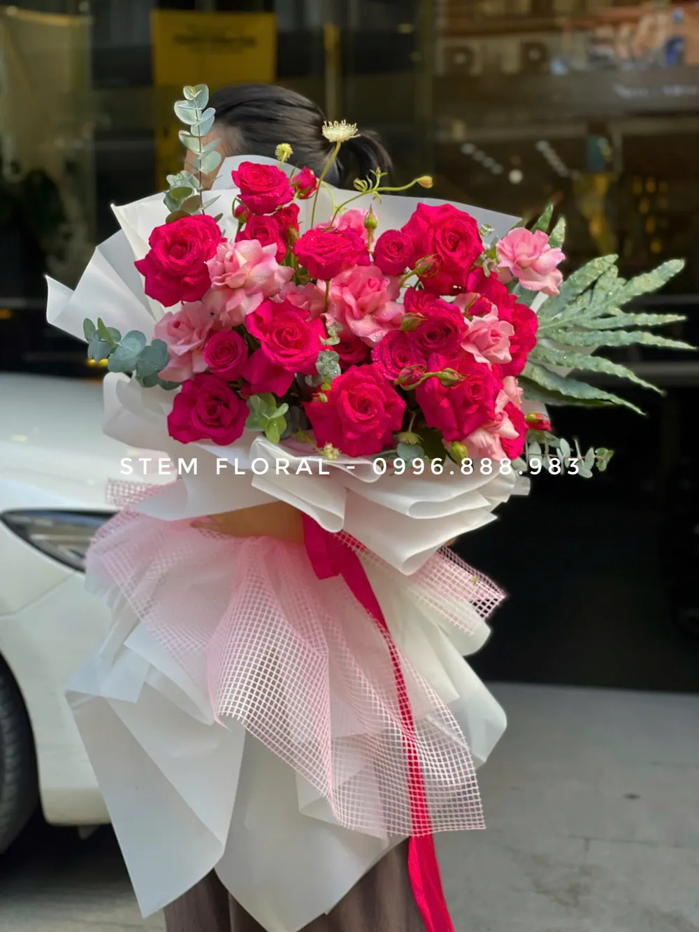 Hồng đỏ trong mây hồng — Hoa hồng đỏ và hồng đậm nổi bật trên lớp giấy trắng hồng xòe rộng, xen những nhánh xanh