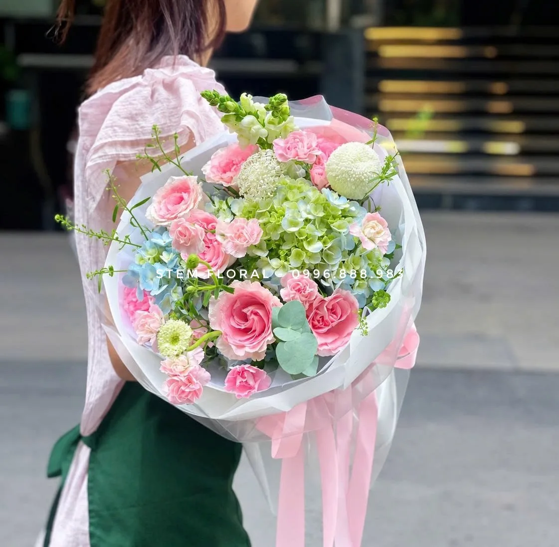 Hồng dịu bên xanh non — Hoa hồng hồng phối cẩm tú cầu xanh non và các điểm hoa sáng màu, gói bằng giấy hồng nhạt trong lớp bọc mỏng