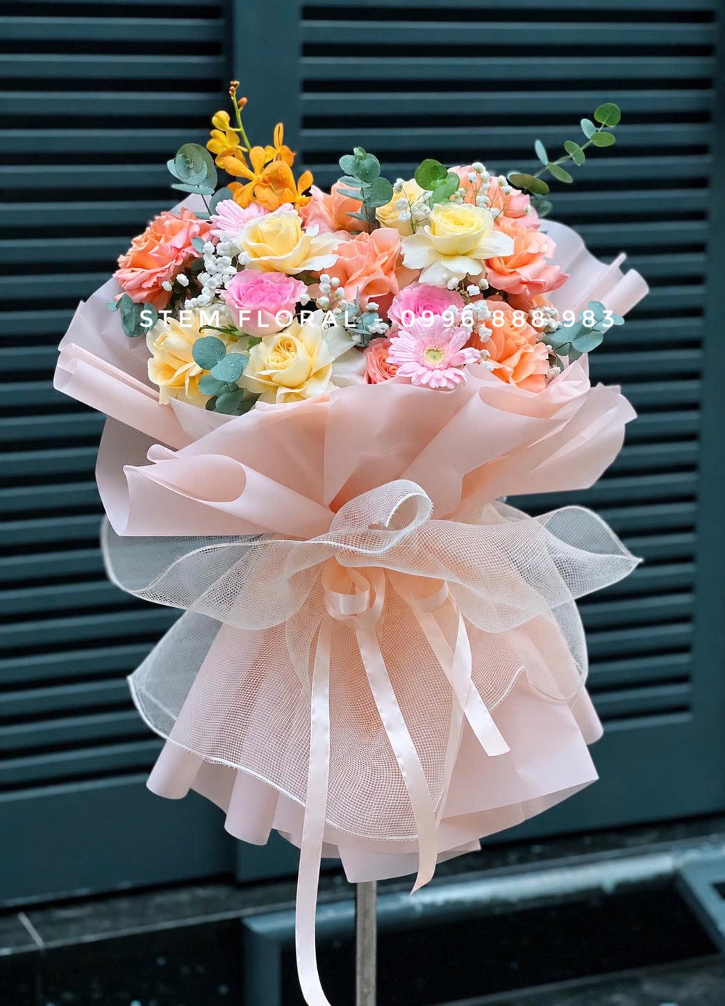 Hoa hồng pastel phối đồng tiền hồng và lá xanh bạc trong giấy màu đào của Stem Floral